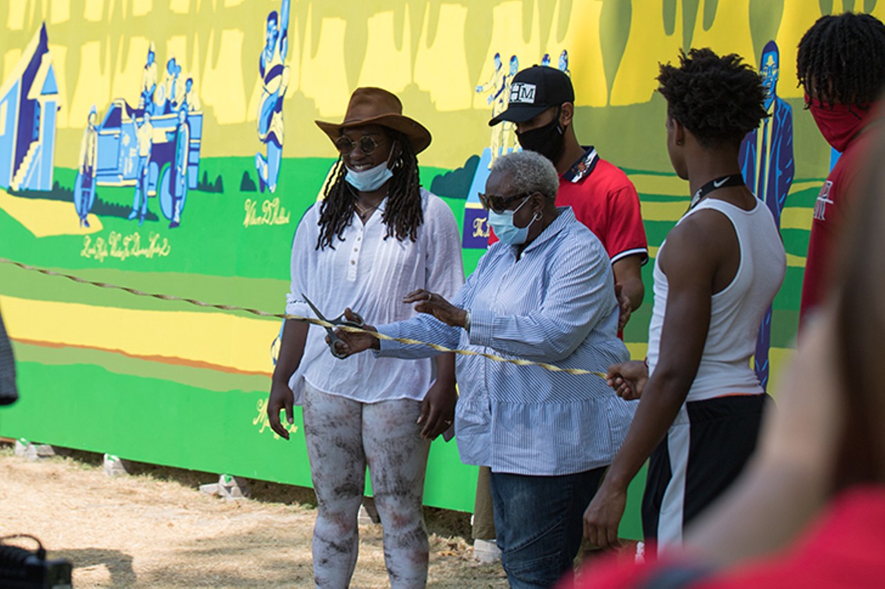 Dolores Lindsay, founder of the Lincoln Heights Health Center and founder, president and CEO of The HealthCare Connection, cuts the ribbon for the dedication and unveiling of "Black Excellence in Zone 15." Lindsay is pictured on the mural.