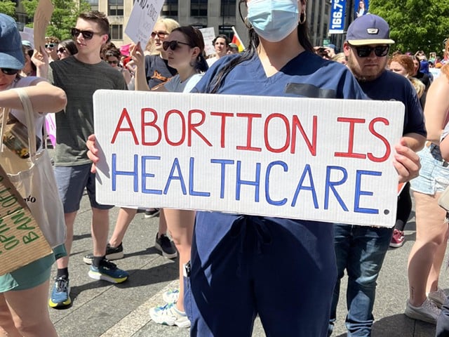 A nurse holds a sign in support of abortion access at a Planned Parenthood rally in Downtown Cincinnati on May 15, 2022.