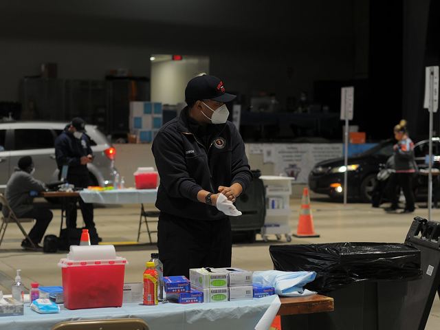 A Columbus Fire Department member dons gloves while working at a mass vaccination site at the Celeste Center in Columbus.