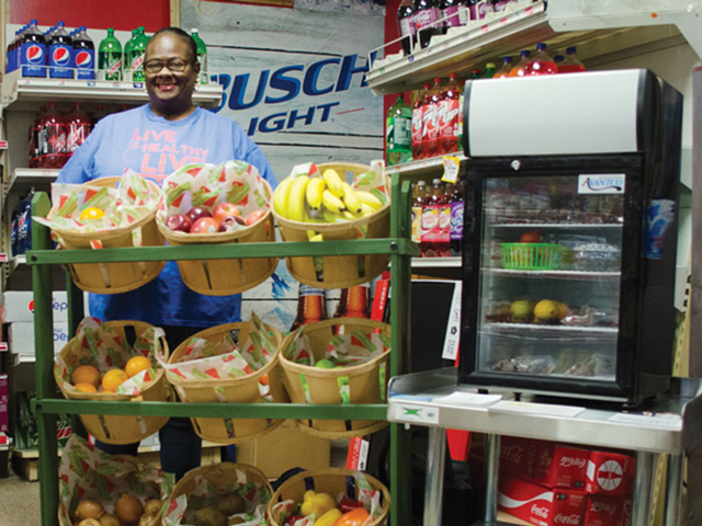 Sylvon Peeples, a community health coach for the Center for Closing the Health Gap, stands behind a recently added display of health food at the Ravine Street Market in Clifton Heights.