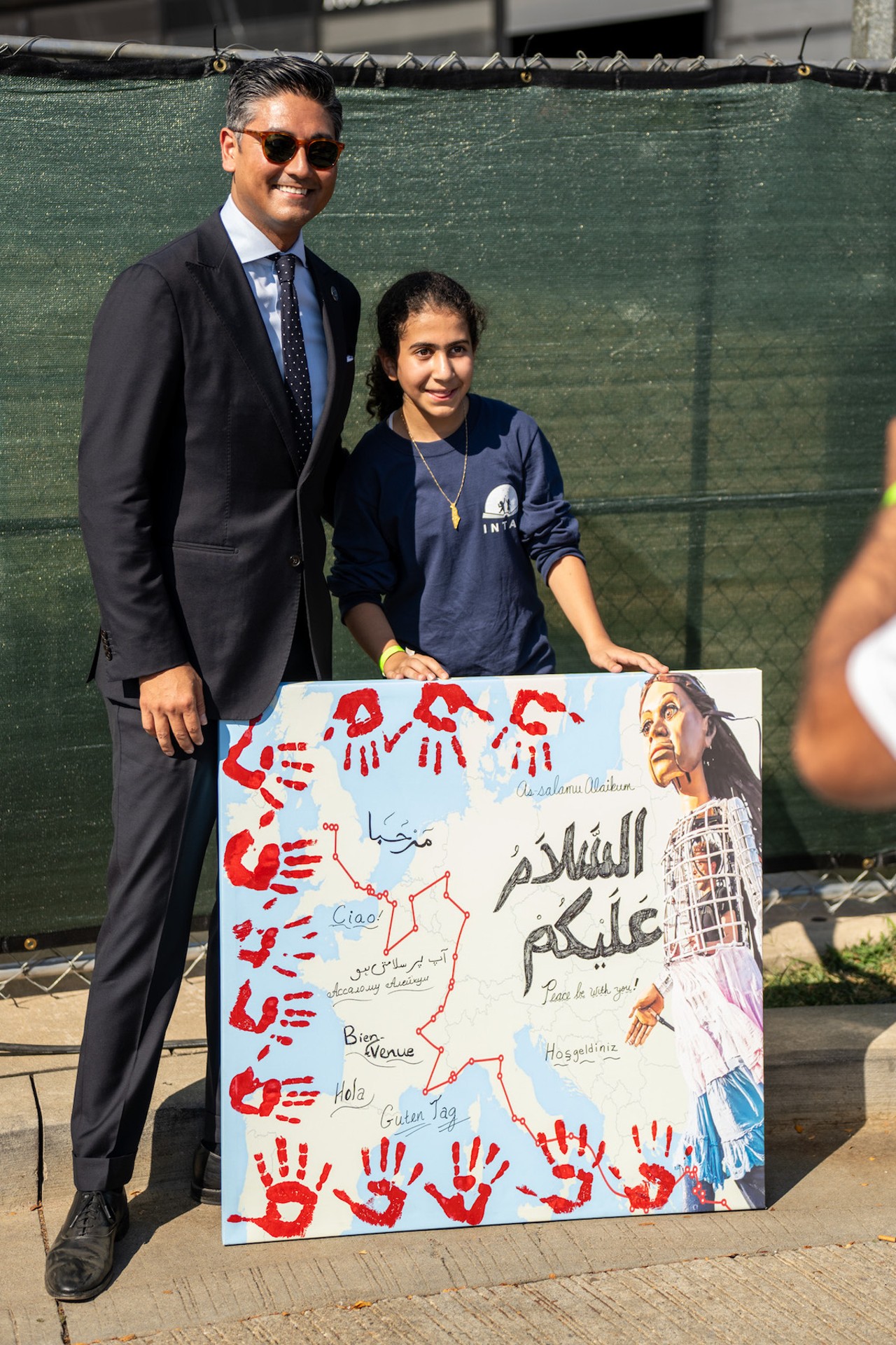 Cincinnati Mayor Aftab Pureval poses with a girl holding a sign during Little Amal's visit to Cincinnati on Sept. 22