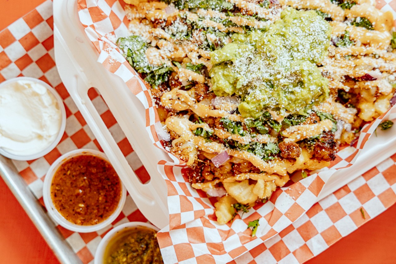 Guti Fries with adobada: fries loaded with guacamole, mozzarella, cilantro, onion and cotija cheese, served with sour cream, roja and verde salsas.