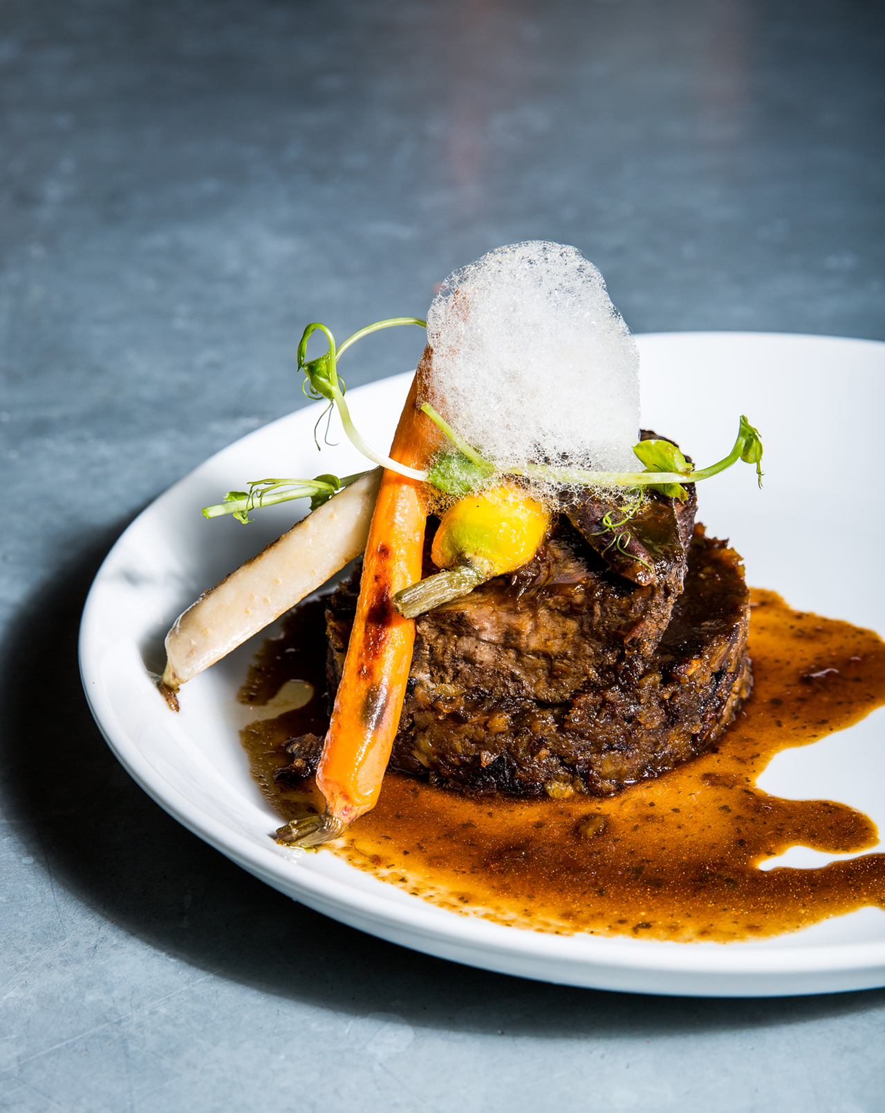 The asado negro de costilla de res: a traditional Venezuelan braised short rib with a panela base (raw sugar that when caramelized has a natural barbecue flavor), served on top of Puerto Rican mofongo (plantains, sofritos and vegetable broth, mashed and seasoned) with heirloom carrots and a sorghum foam.