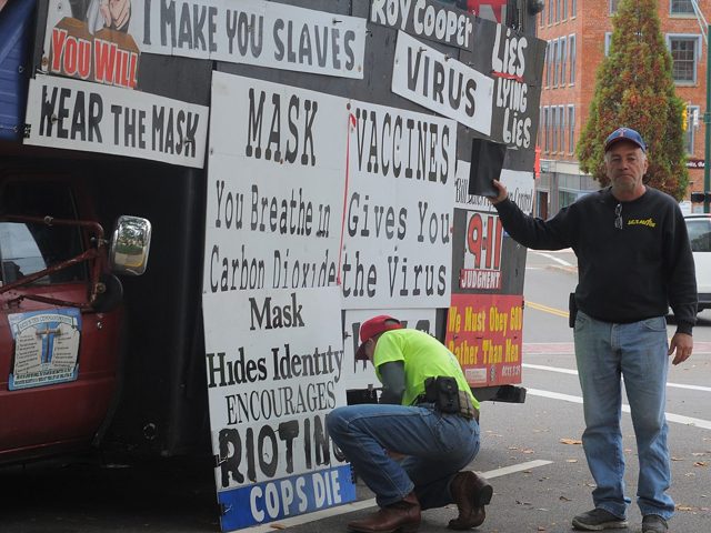 Alan Hoyle, left, adjusts the signs on his truck as Jeff Cline, right, holds up his Bible. The two arrived to Mount Vernon's public square Oct. 24 to counter-program the weekly "Signs on the Square" event.