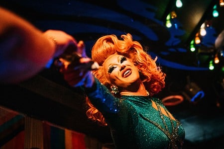 Drag performer Aubrey Damned reaches for a tip from an audience member during a performance.