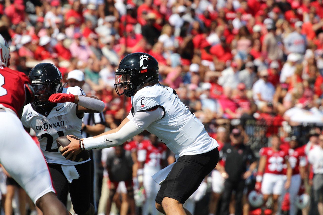 UC quarterback Brendan Sorsby hands the ball off to UC running back Corey Kiner.