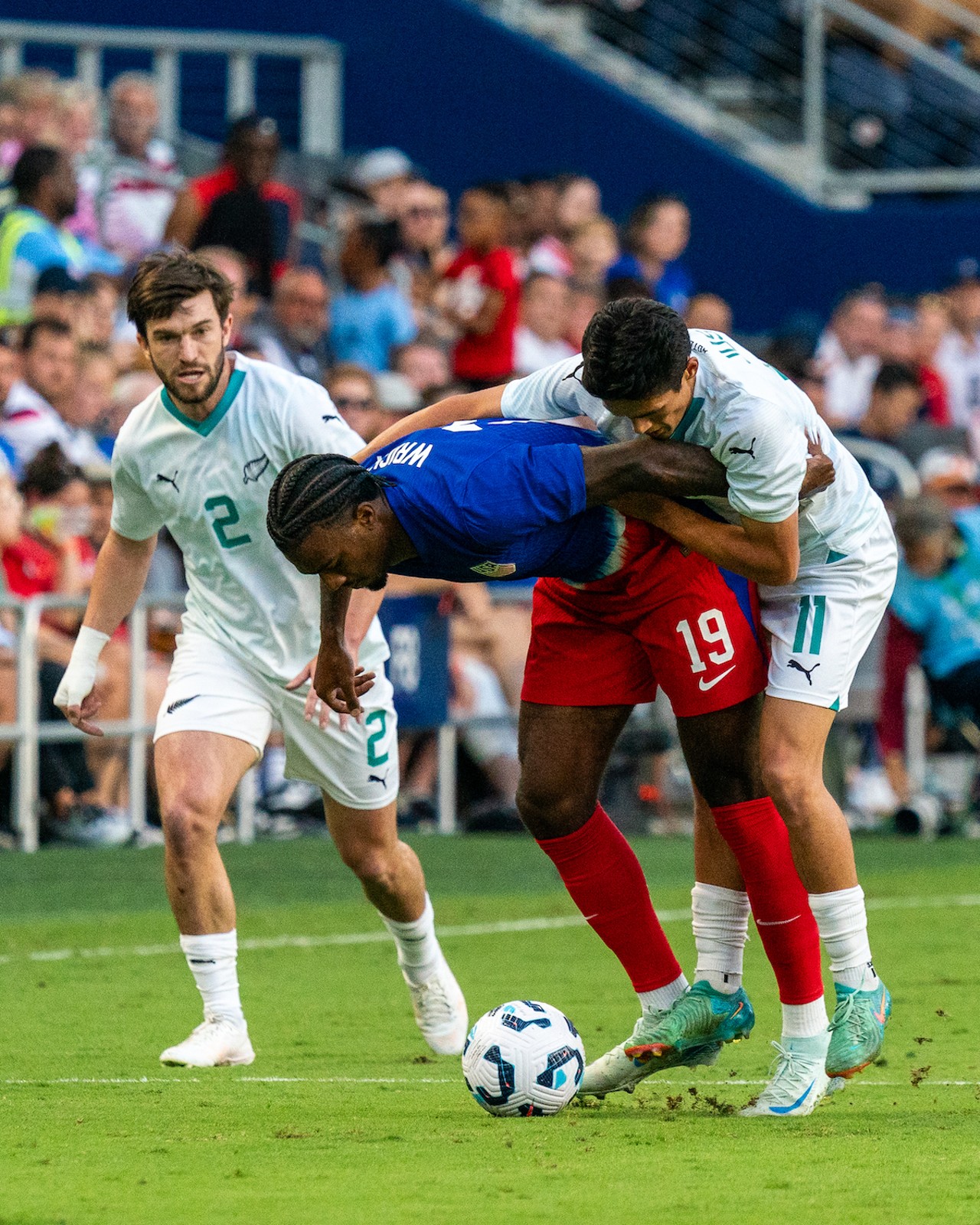 Haji Wright fighting off New Zealand players draped around the USA forward.