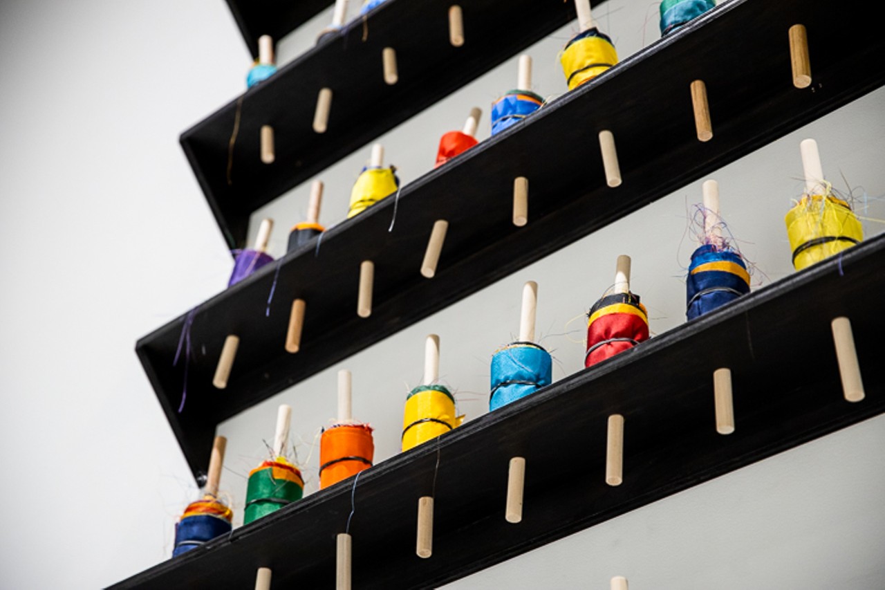 Above the "RopeWalk" work tables is a piece titled "Lullabies are for Children," which is made up of colorful bobbins on sumi ink-stained shelves. It's meant to parallel Audre Lorde's poem "The Same Death Over and Over or Lullabies for Children," in her 1978  book The Black Unicorn.