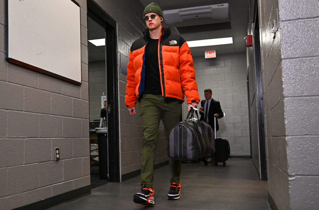 Cincinnati Bengals quarterback Joe Burrow wears an orange puffy jacket, olive trousers and a beanie before the AFC divisional game against the Buffalo Bills on Jan. 22, 2023.