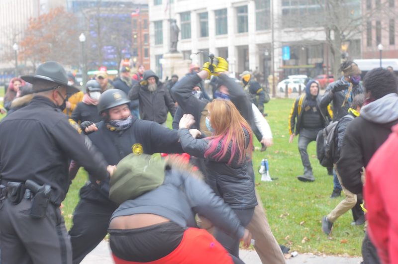Clashing protesters brawl for the second time Wednesday on the Ohio statehouse campus. A man in Proud Boys gear winds up a punch with his right fist clenched. - Photo: Jake Zuckerman