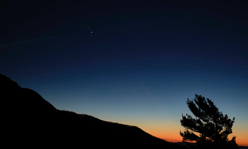 Saturn, top, and Jupiter, below, are seen after sunset from Shenandoah National Park, Sunday, Dec. 13, 2020, in Luray, Virginia. The two planets are drawing closer to each other in the sky as they head towards a “great conjunction” on December 21, where the two giant planets will appear a tenth of a degree apart. - Photo: NASA/ Bill Ingalls