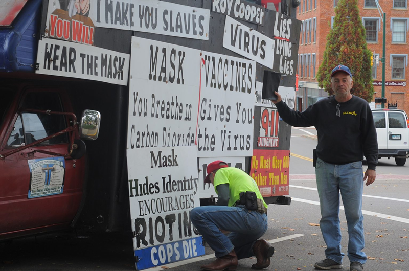 Alan Hoyle, left, adjusts the signs on his truck as Jeff Cline, right, holds up his Bible. The two arrived to Mount Vernon's public square Oct. 24 to counter-program the weekly "Signs on the Square" event. - Photo: Jake Zuckerman