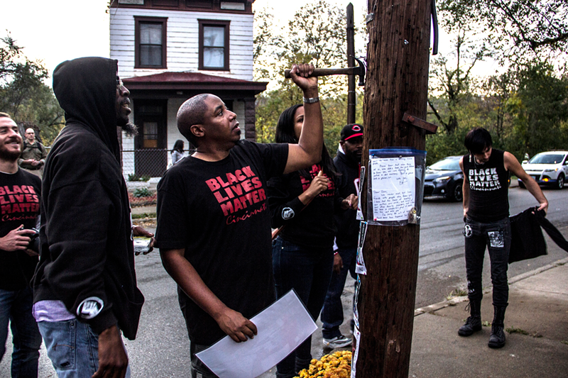 Brian Taylor of Cincinnati Black Lives Matter preparing to hang a portrait of Sam DuBose at the spot where officials removed an earlier memorial. - Nick Swartsell