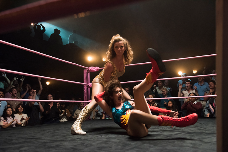 Betty Gilpin, standing, wrestles Alison Brie in "GLOW." - Photo: Erica Parise / Netflix