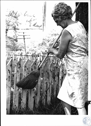 A historic photo of Mrs. Bernad Long swatting cicadas off fence - PHOTO: KENTON COUNTY PUBLIC LIBRARY