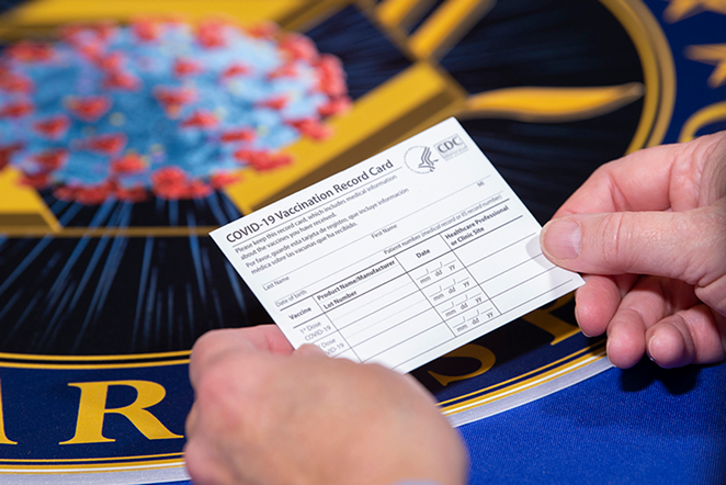 A Department of Health and Human Services employee holds a COVID-19 vaccine record card - Photo: EJ Hersom, DOD