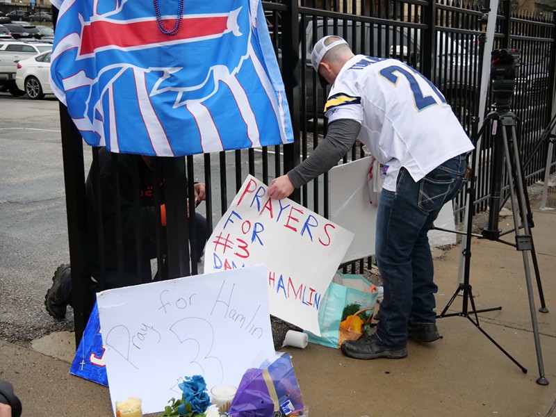 Brandon Metzger works to fix signs of support for Buffalo Bills’ safety Damar Hamlin outside UC Medical Center on Jan. 3. He said both the Bengals and the Bills are more than NFL teams, they're family. - Photo: Madeline Fening