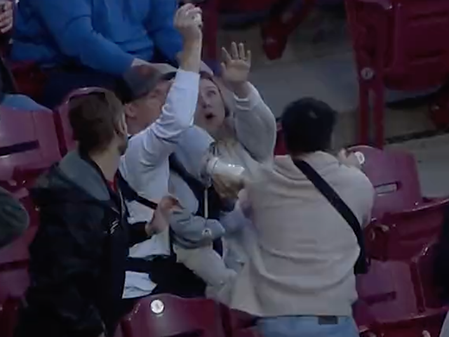 Jacob Kingsley catches a foul ball while feeding his infant son during a Cincinnati Reds game at Great American Ball Park on April 26, 2022.